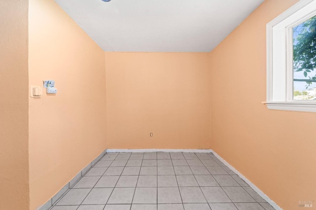 empty room with light tile patterned floors and baseboards