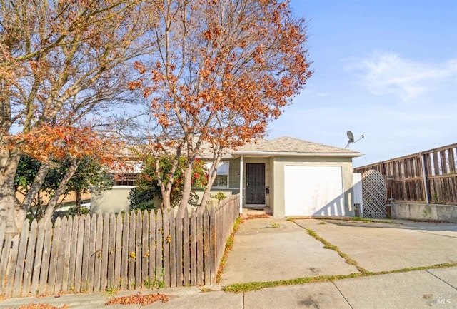 view of front of home with a garage, a fenced front yard, driveway, and stucco siding