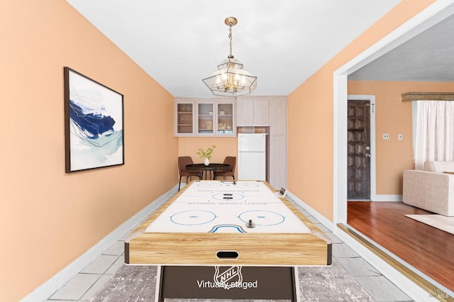 recreation room with light tile patterned floors, a notable chandelier, and baseboards