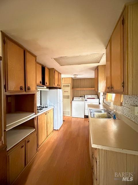 kitchen featuring washer / dryer, white appliances, light hardwood / wood-style floors, and sink