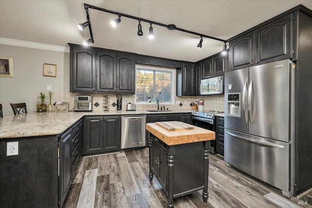 kitchen featuring sink, wood counters, a textured ceiling, appliances with stainless steel finishes, and ornamental molding