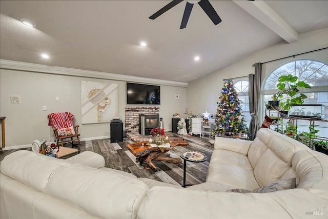 living room featuring ceiling fan, hardwood / wood-style floors, beamed ceiling, and a brick fireplace