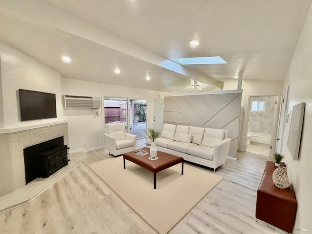 living room featuring lofted ceiling with skylight, light hardwood / wood-style flooring, a wall mounted air conditioner, and a brick fireplace