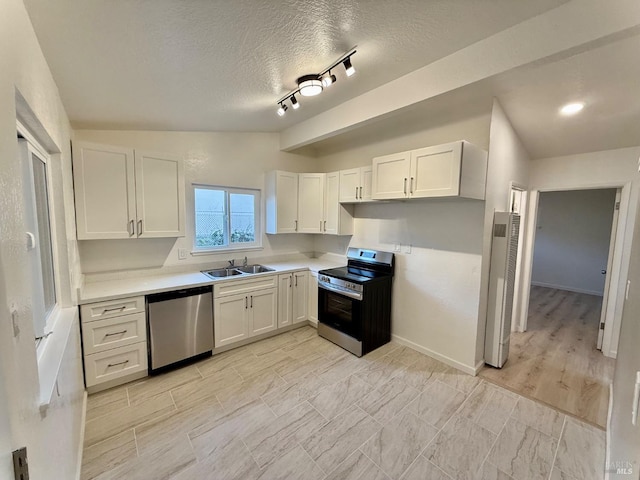 kitchen featuring a textured ceiling, stainless steel appliances, white cabinetry, and sink