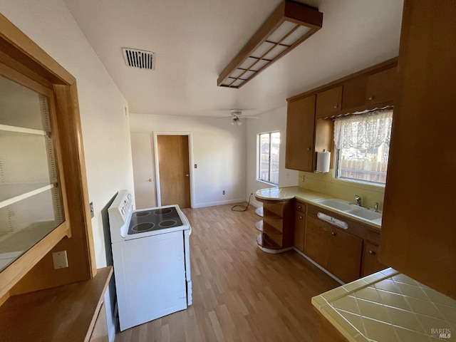 kitchen featuring sink, light hardwood / wood-style flooring, ceiling fan, white range with electric stovetop, and kitchen peninsula