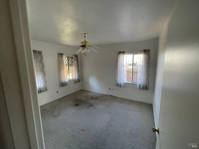 carpeted empty room with baseboards and ceiling fan