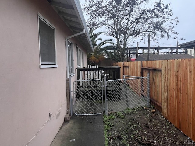 view of property exterior with stucco siding, a gate, and fence