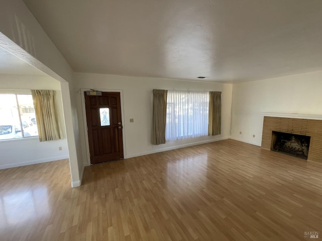 unfurnished living room featuring baseboards, light wood-type flooring, and plenty of natural light