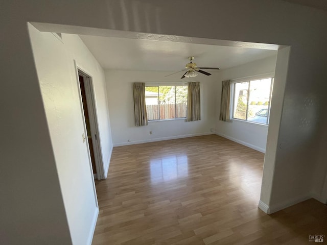 unfurnished room featuring ceiling fan, baseboards, and light wood-type flooring