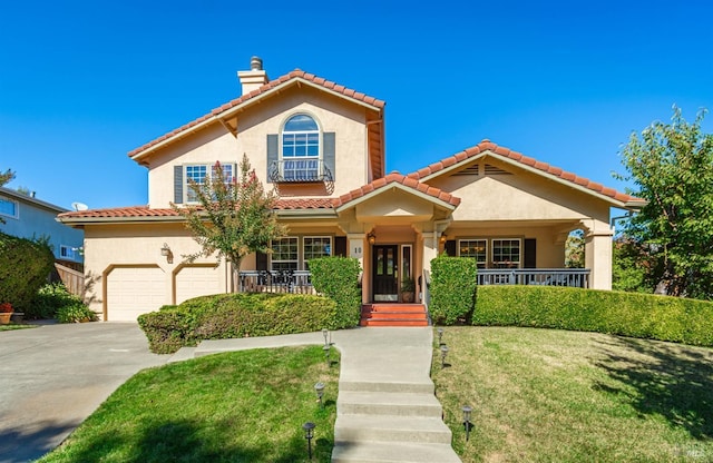 mediterranean / spanish home featuring covered porch, a garage, and a front yard