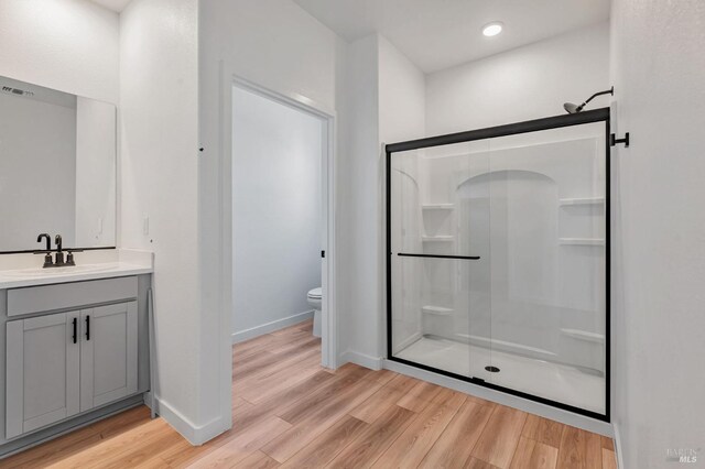 full bathroom with vanity, toilet, wood finished floors, and a stall shower