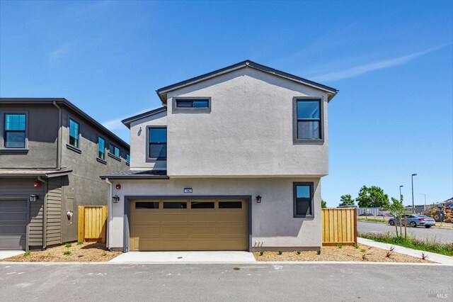 view of front facade with a garage, stucco siding, and fence