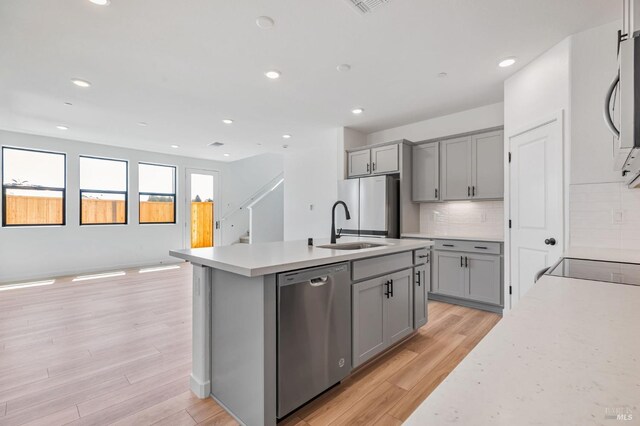 kitchen with light wood-style floors, a sink, appliances with stainless steel finishes, and gray cabinetry