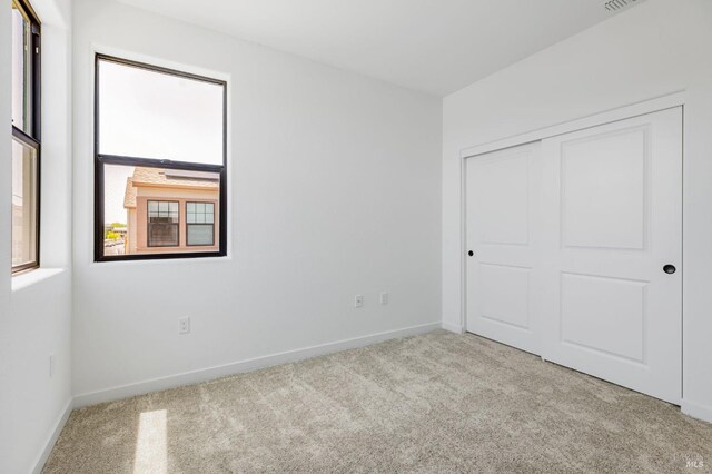 unfurnished bedroom featuring carpet floors, baseboards, and a closet
