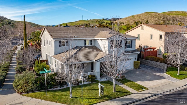 view of front of home with stucco siding, a front lawn, a mountain view, concrete driveway, and an attached garage