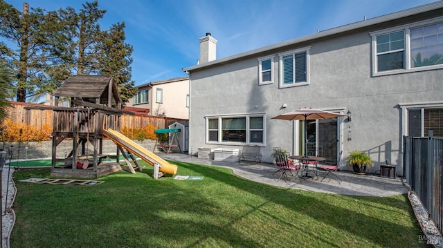 rear view of house featuring a playground, a patio area, and a lawn