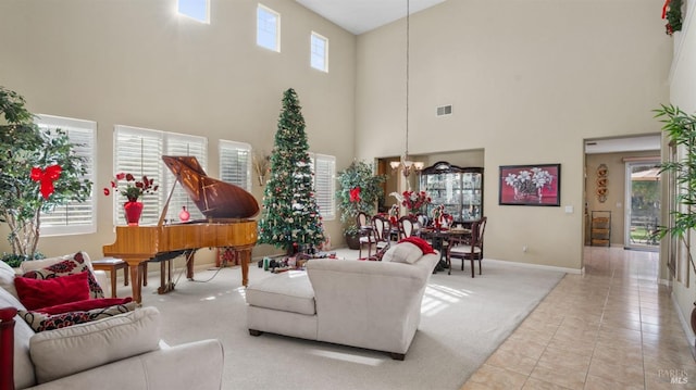 living room with light tile patterned floors, an inviting chandelier, a wealth of natural light, and a high ceiling