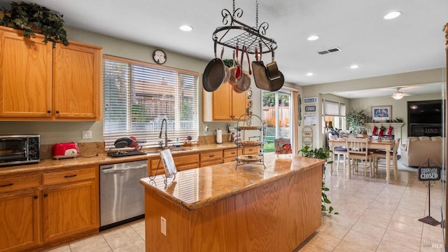 kitchen featuring light stone countertops, ceiling fan, sink, dishwasher, and a kitchen island