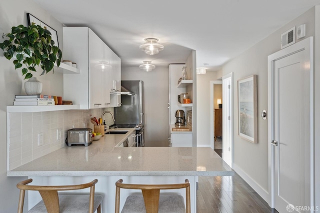 kitchen featuring kitchen peninsula, white cabinets, and a breakfast bar area