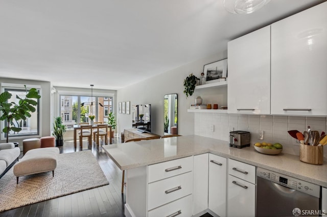 kitchen featuring white cabinets, dishwasher, light stone counters, kitchen peninsula, and hanging light fixtures