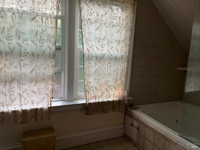 bathroom with tile patterned flooring, tiled bath, and a healthy amount of sunlight