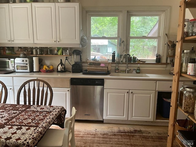 kitchen featuring white cabinets, dishwasher, wood-type flooring, and sink