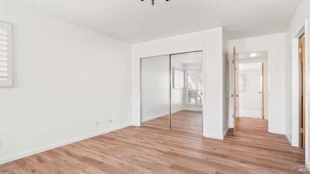 unfurnished bedroom featuring a closet and light wood-type flooring