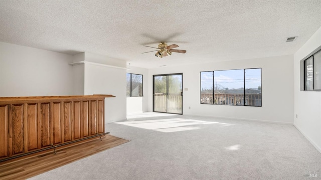 unfurnished room with ceiling fan, light colored carpet, and a textured ceiling