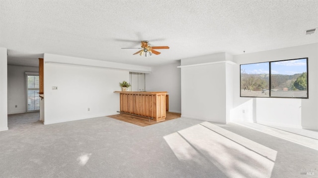 carpeted spare room featuring ceiling fan and a textured ceiling