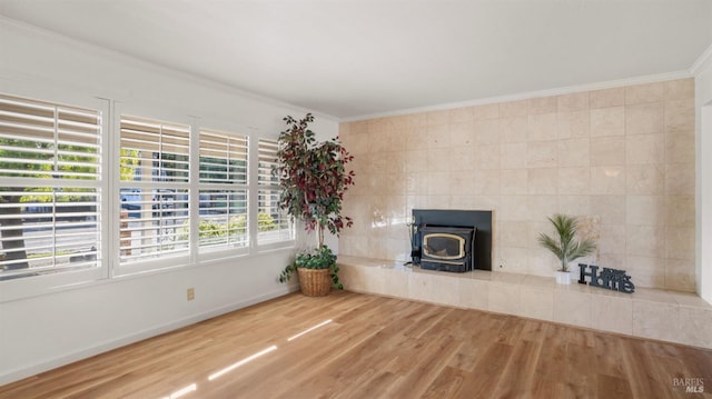 unfurnished living room featuring hardwood / wood-style flooring, a wood stove, crown molding, and tile walls