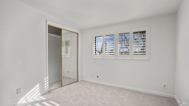 unfurnished bedroom with light colored carpet and a closet