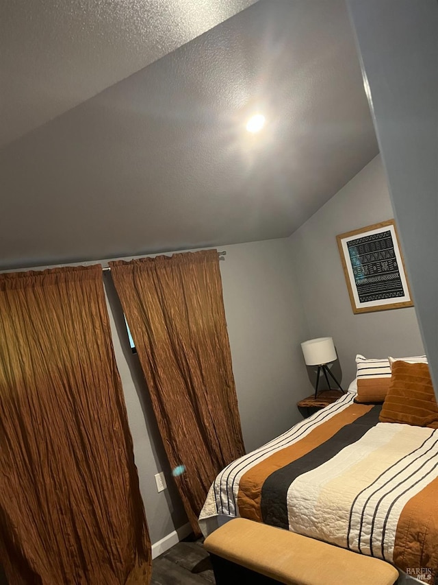 bedroom with dark hardwood / wood-style flooring and lofted ceiling