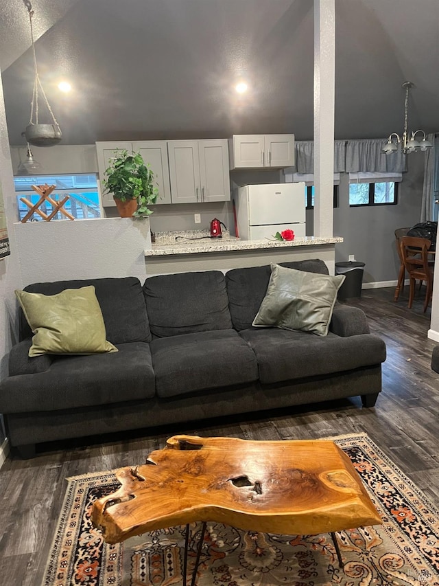 living room with vaulted ceiling, dark hardwood / wood-style floors, and an inviting chandelier