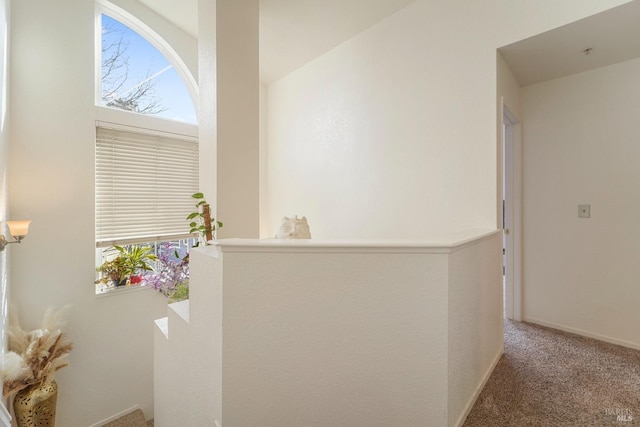 corridor featuring carpet, baseboards, and an upstairs landing