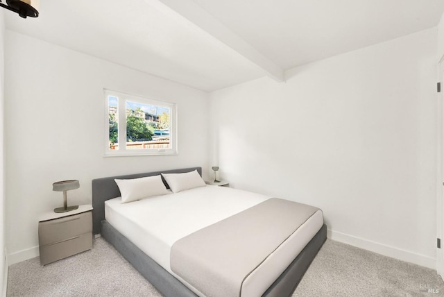 bedroom with beamed ceiling and light colored carpet