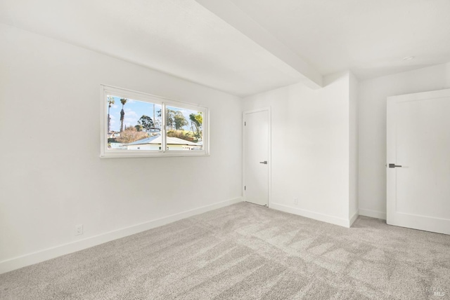 unfurnished room featuring beam ceiling and carpet