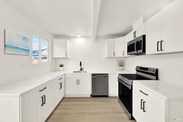 kitchen with sink, white cabinetry, light wood-type flooring, appliances with stainless steel finishes, and beamed ceiling