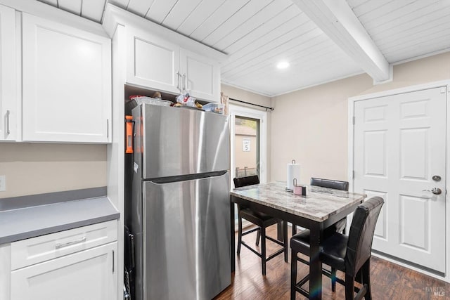 kitchen featuring beam ceiling, white cabinets, dark hardwood / wood-style flooring, and stainless steel refrigerator