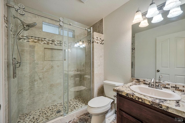 bathroom with vanity, toilet, a shower with shower door, and a textured ceiling