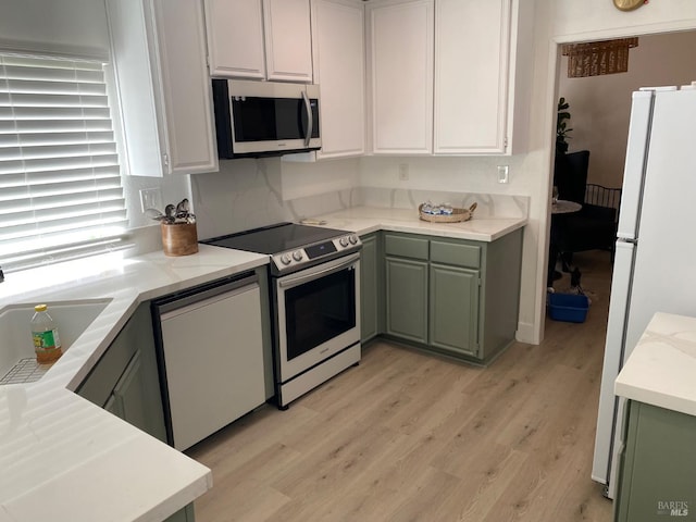 kitchen featuring a sink, stainless steel appliances, light countertops, and green cabinetry