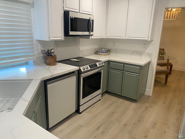 kitchen featuring light wood finished floors, white cabinetry, stainless steel appliances, and green cabinetry