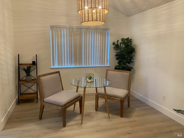 living area featuring a chandelier, vaulted ceiling, baseboards, and wood finished floors