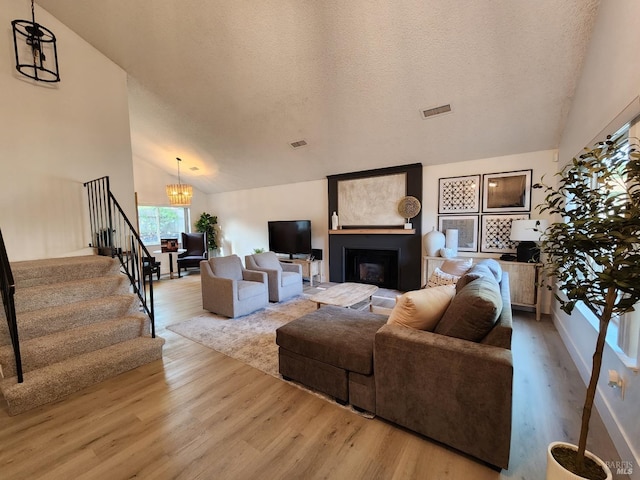 living area with light wood-style floors, visible vents, a fireplace, and stairs