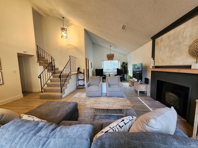 living room with a textured ceiling, a fireplace, wood finished floors, baseboards, and stairway