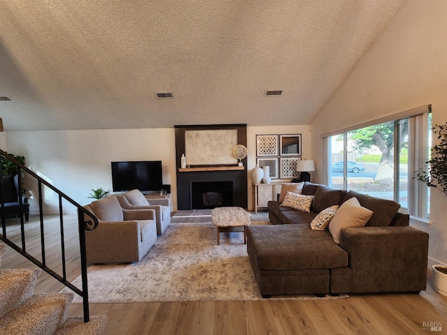 living area featuring vaulted ceiling, stairway, wood finished floors, and visible vents