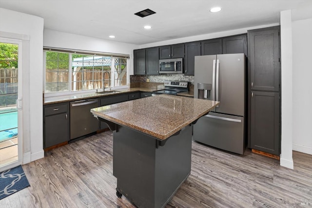 kitchen with a kitchen bar, appliances with stainless steel finishes, dark stone counters, sink, and a kitchen island