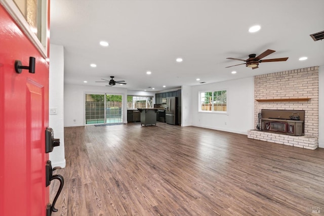 unfurnished living room with a healthy amount of sunlight, ceiling fan, and dark wood-type flooring