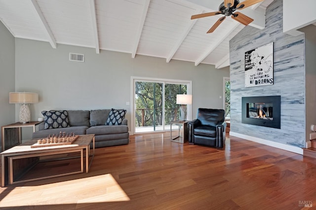 living room featuring vaulted ceiling with beams, ceiling fan, hardwood / wood-style floors, and a tile fireplace