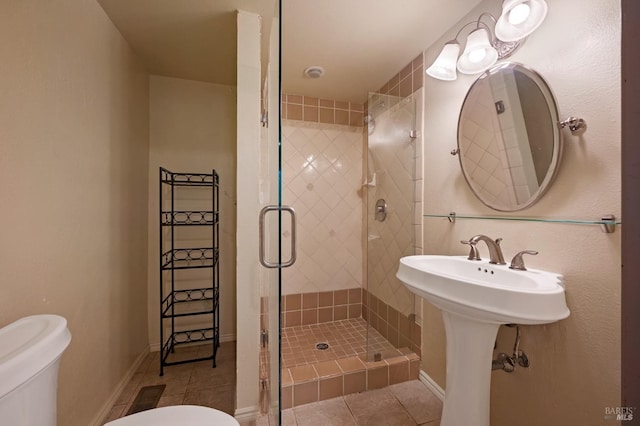 bathroom with sink, tile patterned flooring, a shower with door, and toilet