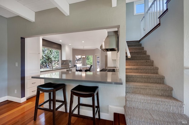 kitchen featuring kitchen peninsula, white cabinetry, and beamed ceiling